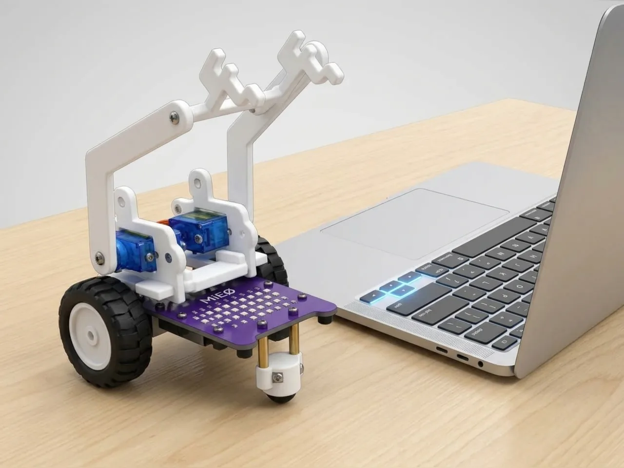 MIEO with a single servo arm raised, beside a laptop keyboard