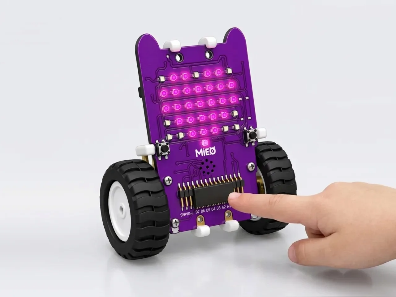 A finger touching one of MIEO's four touch pads while its display shows a heart